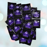 A collection of black ID Superior Feel Condoms packets, featuring purple branding and the letters "ID," is displayed against a softly blurred backdrop of light blue and white circular bokeh, evoking a sense of assurance in sexual satisfaction and birth control.